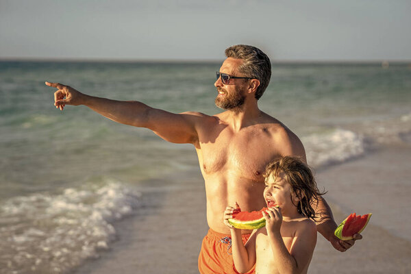 Отцовство и сын дети наслаждаются морем вместе. Отец и сын держат арбуз. Отец показывает своему сыну будущее. Отцовство и сын на пляже. воспитать ребенка.