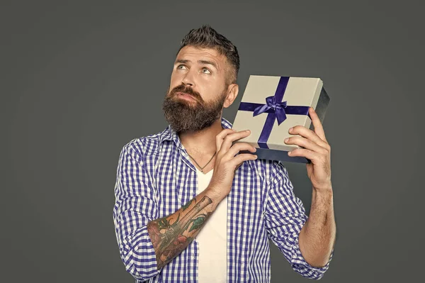 dreamy mature bearded man with present box on grey background.