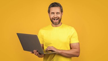 Stüdyodaki mutlu adam programcısı. Dizüstü bilgisayarlı insan programcısının fotoğrafı. İnsan programcısı sarıda izole edildi. Arka plandaki adam programcısı.