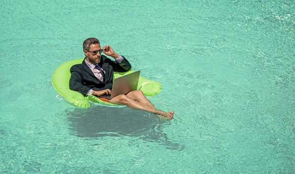 man trader work and relax. man trader work and relax in swimming pool. man trader work and relax with laptop.