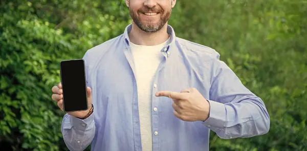 man presenting and pointing finger on smartphone screen with copy space. presenting smartphone. man presenting smartphone. man presenting smartphone outdoor.