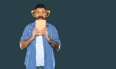 Parti gözlüklü komik sakallı adam kitabı tutuyor..