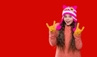 Kış şapkalı mutlu kız. Kış modası. Gençler örgü örer. Açık hava yaşam tarzı. Kış sıcacık şapkalı genç kız kırmızıda izole edilmiş. Serin gün.