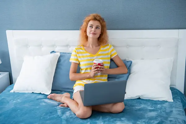 dreamy woman freelancer with coffee work at home on laptop. freelancer woman work at home. home work for freelancer. woman in bed with laptop.