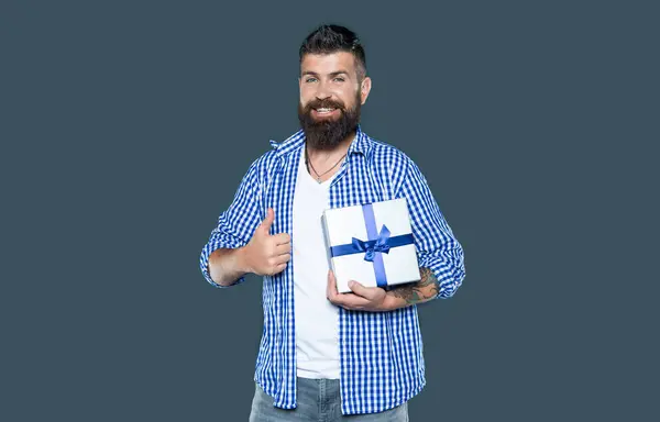 stock image mature bearded guy with present box on grey background. birthday gift.