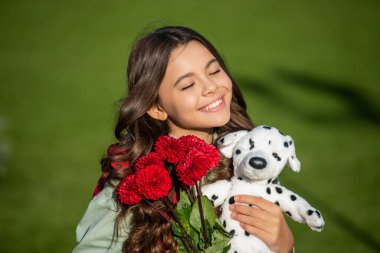 Genç kız oyuncağı tutuyor ve dışarıda buketi düşürüyor. Düşen buketi olan genç bir kızın fotoğrafı. Dışarıda güz çiçekli genç bir kız. Sonbahar çiçekli genç kız buketi.