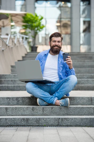 glad man freelancer has video call outside. man freelancer has video call at coffee break. man freelancer has video call outdoor. man freelancer has video call on laptop.