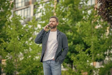 Akıllı telefondan arayan ve konuşan bir adamın görüntüsü. Adamın dışarıda akıllı telefonları var. Sokakta akıllı telefon görüşmesi yapan bir adam. Adam dışarıdaki akıllı telefondan arıyor..