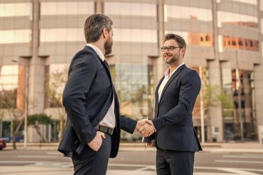 Tokalaşma ile uğraşan iki iş adamı imajı. İki iş adamı el sıkışma ile ilgilenir. İki işadamı el sıkışma işini dışarıda halleder. Takım elbiseli iki işadamı el sıkışmayla ilgileniyor..