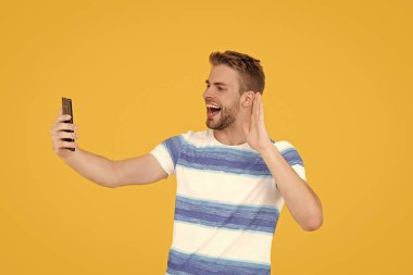 Telefonu olan mutlu bir milenyum adamı. Milenyum adamı stüdyoda telefonla selfie çekiyor. Milenyum adamı selfie çekmek için telefon kullanıyor. Genç milenyum adamı cep telefonunu selfie ya da sosyal medyada gezinmek için kullanıyor..