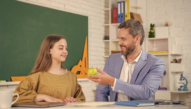 Sınıfta mutlu bir çocuk ve özel öğretmen elmayı paylaşıyor..