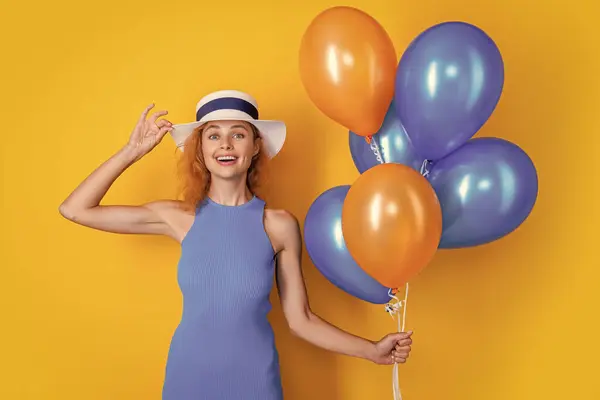 amazed woman with balloons at summer birthday isolated on yellow. woman with balloons at summer birthday in studio. woman with balloons at summer birthday. photo of woman with balloons at summer