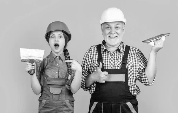 stock image happy amazed child and granddad plasterer in helmet on yellow background.