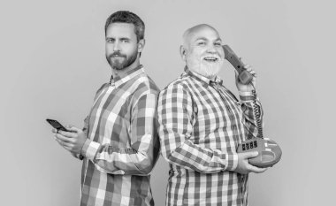 Telefon ve telefon teknolojisi olan adamların görüntüsü. Sarıya karşı teknolojisi olan adamlar izole edilmiş. Stüdyoda teknolojisi olan adamlar var. Arka planda vs teknolojisi olan erkekler.