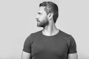 Beyaz adamın sakallı yüzünün profil fotoğrafı. Kirli sakallı beyaz adam tişört giyiyor. Gri arka planda sakallı beyaz bir adam var. Stüdyoda sakalı olan beyaz bir adam..