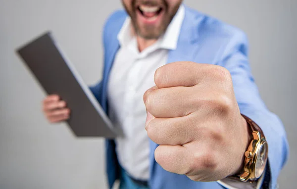 Angry and aggressive man threatening with fist. Angry businessman, closeup. Businessman hold laptop and threatening with fist. Business boss man feel anger and aggression. Anger management.