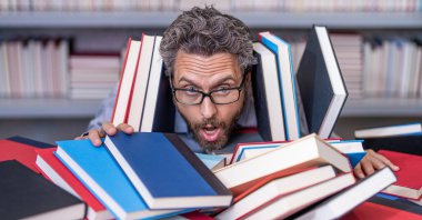 Çok çalışan milenyum öğrencisi kitap okuyor. Çok çalışan erkek öğrenci kitapçıda ya da okul kütüphanesinde kitap okuyor. Okulda edebiyat öğretmeni ve kitap. Bilgi günü. Okul sınavına hazırlan. kişisel eğitim.