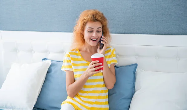 surprised woman with coffee talk on phone. woman at home talking on phone. phone talk at home of woman.