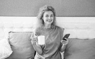 Kahveli gülümseyen kadın telefonda konuşuyor. Kadın telefonuyla evde sohbet ediyor. Kadının evinde telefon görüşmesi..