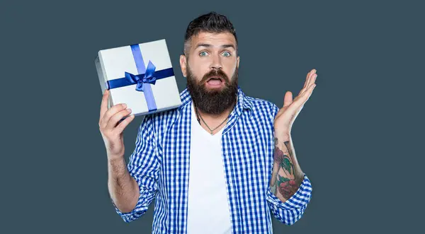 stock image confused mature bearded man with present box on grey background.