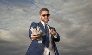 Zengin milyoner bir adam, parasıyla gökyüzünü işaret ediyor. Parası olan zengin bir milyoner. Takım elbiseli zengin milyoner adam. Paralı zengin bir milyonerin fotoğrafı..