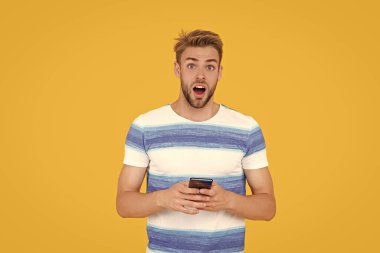 Şok olmuş bir adam mesajlaşmak veya mesaj atmak için telefonunu kullanır. Adam etkili iletişim kurmak için telefonu kullanıyor. Adamın telefon bağlantısı var. Telefonlu adamın dijital iletişimi.