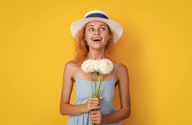 Stüdyoda elinde kadın çiçekleri olan mutlu bir kız. Arka planda kadınlar günü çiçekleri olan kız. Kadınlar günü kasımpatı çiçekli bir kızın fotoğrafı. Kadınlar günü çiçekli kız sarıda soyutlanmış..