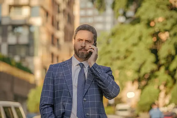 caucasian businessman having phone call in the street. businessman call on phone outside. photo of businessman call on phone and talk. businessman has phone call outdoor.