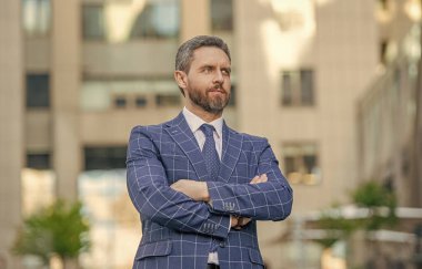 Kravatlı çapraz elli iş adamının fotoğrafı. İş adamı açık havada. Kentsel geçmişi olan bir iş adamı. Sokakta ceketli bir işadamı..