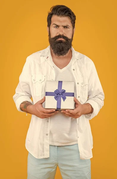 man offer sale gift on background. photo of man offer sale gift box. bearded man offer sale gift isolated on yellow. man offer sale gift in studio.