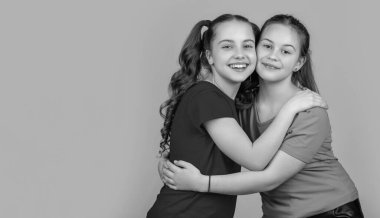 Sarı arka planda kucaklaşan mutlu çocuklar. kız kardeşlik.