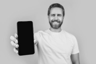 Arka planda akıllı telefon uygulaması gösteren bir adam seçici odağı. Stüdyoda akıllı telefon uygulaması gösteriyor. Akıllı telefon uygulaması gösteren bir adamın fotoğrafı. Akıllı telefon uygulaması gösteren adam sarıda izole edildi.