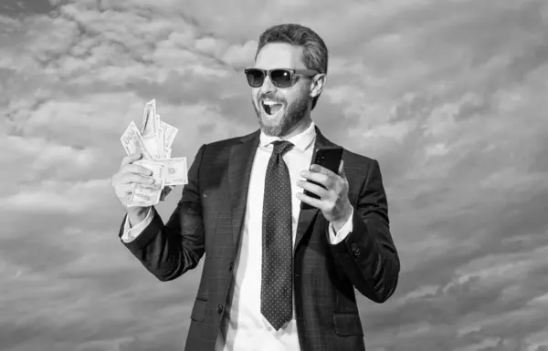 Successful man lawyer happy shouting with cash money and smartphone. Cash payment or smartphone payment. Cash purchase. Paying in cash for smartphone.
