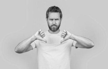 Arka planda hoş olmayan jestleri olan ciddi bir adam. Stüdyoda hoş olmayan bir jest yapan adam. Sevimsiz jestli bir adamın fotoğrafı, baş parmağını indir. Hoşlanmayan adam sarıyı izole eder..