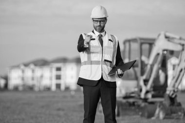 İnşaat mühendisliği mühendisi miğfer takıyor, parmağıyla işaret ediyor. İnşaat mühendisliğindeki mühendisin fotoğrafı. İnşaat mühendisliğinde mühendis. İnşaat mühendisliğinde mühendis..