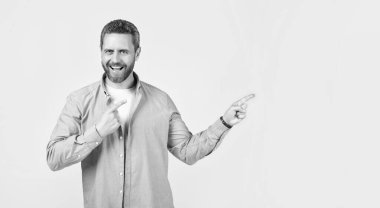 Neşeli adam stüdyoya işaret ediyor ve reklam veriyor. Bir adamın işaret ettiği ve reklam verdiği fotoğraf. Adam işaret ediyor ve reklam veriyor. Gri üzerine izole edilmiş bir reklam sunan adam.