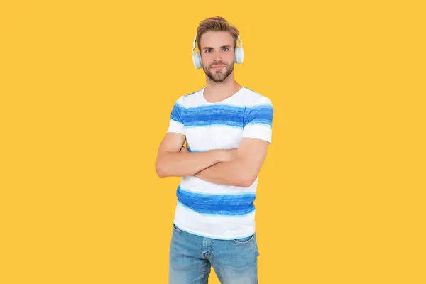 smiling man relaxes and listens to music in studio. man uses his wireless headphones to listen to music. man listen and enjoys live music. man listens to music on his headphones isolated on yellow.
