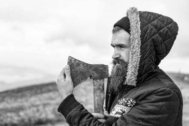 Keskin baltası olan sakallı bir oduncu. Dağda balta tutan sakallı bir oduncunun fotoğrafı. Sakallı adam dışarıda baltayı tutuyor. Sakallı adamın baltası var..