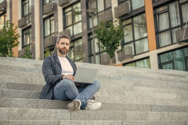 Sokakta fotokopi alanı olan serbest çalışan bir adam. Dışarıda polisle serbest çalışan bir adam. Bilgisayarlı serbest çalışan adamın fotoğrafı. Dışarıda dizüstü bilgisayarı olan serbest çalışan bir adam..