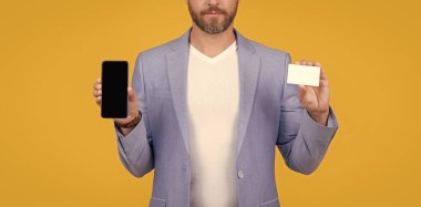 Çevrimiçi ekommerce ödeyen kırpılmış adam sarıda izole edilmiş. Stüdyoda internetten ödeme yapan adam. Ekommerce konsepti. İnternetten ödeme yapan adam, Ecommerce. İnternet üzerinden ödeme yapan adam cep telefonu ve ekommerce kartı ile fotokopi alanı.