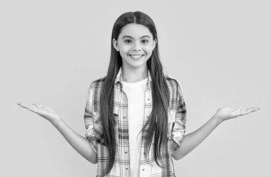 Uzun saçlı, kareli gömlek giyen ve ürün sunan genç bir kızın fotoğrafı. Sarıda izole edilmiş genç bir kız. Stüdyodaki genç kız. Arka plandaki genç kız.