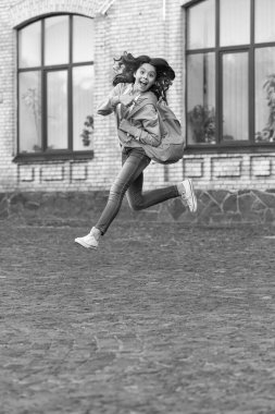 Okul kızının çocukluk fotoğrafı sırt çantasıyla ve eğitimle atlama. liseli kız dışarı atlıyor. Liseli kız çocukluğunu dışarıda atlamış. Liseli kız çocukluğunu sokakta atlamış..