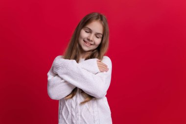 Kız çocuğu kırmızı üzerine kalın bir kazak giyer. Mutlu şık bir çocukluk dilerim. Kazaklı genç kız. Kış modası. Örgü elbiseli kız. Genç bir çocuğun portresi kalın kışlık giysiler giyer. Kaşmir kazak.