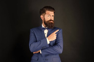 serious man in tuxedo bow tie. bride groom in formalwear pointing finger on black background. male formal fashion. copy space.