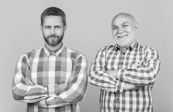 two generation family men isolated on yellow. two generation family men in studio. two generation family men on background. photo of two generation family men wear checkered shirt.