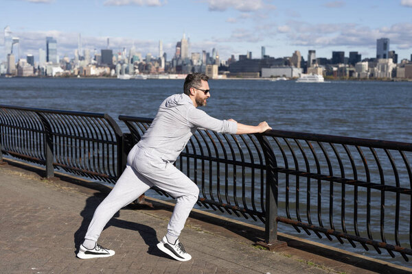 Stretching routine of sportsman outdoor in NY. Sportsman stretching muscles after running. Sportsman stretch to improve flexibility. Sport man stretching warm up for workout. Functional flexibility.