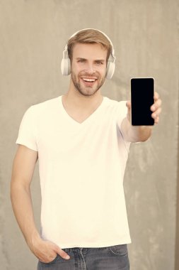Mutlu adam sunar. Müzik uygulaması, kopyalama alanı. Adam dışarıda müzik uygulamasını sunuyor. Adam akıllı telefondan müzik uygulamasını sunuyor. Kulaklıkla müzik uygulaması sunan bir adamın fotoğrafı.