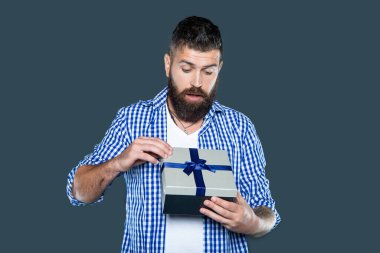 Meraklı, olgun, sakallı, gri arka planda mevcut kutusu olan bir adam..