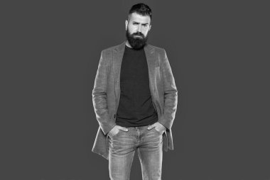 Zarif sakallı, olgun bir adam gri arka planda rahat giyinir..