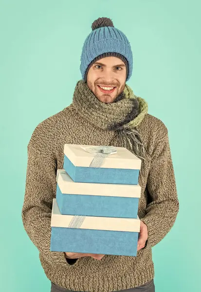happy man hold present box isolated on blue background. man hold present box in studio. man hold present box for christmas holiday. man in winter clothes hold present box.